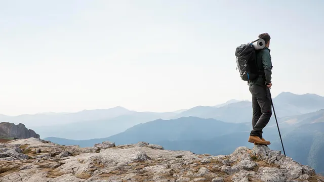 Vandrer ser utover fjellene, med ryggsekk og vandrestav.